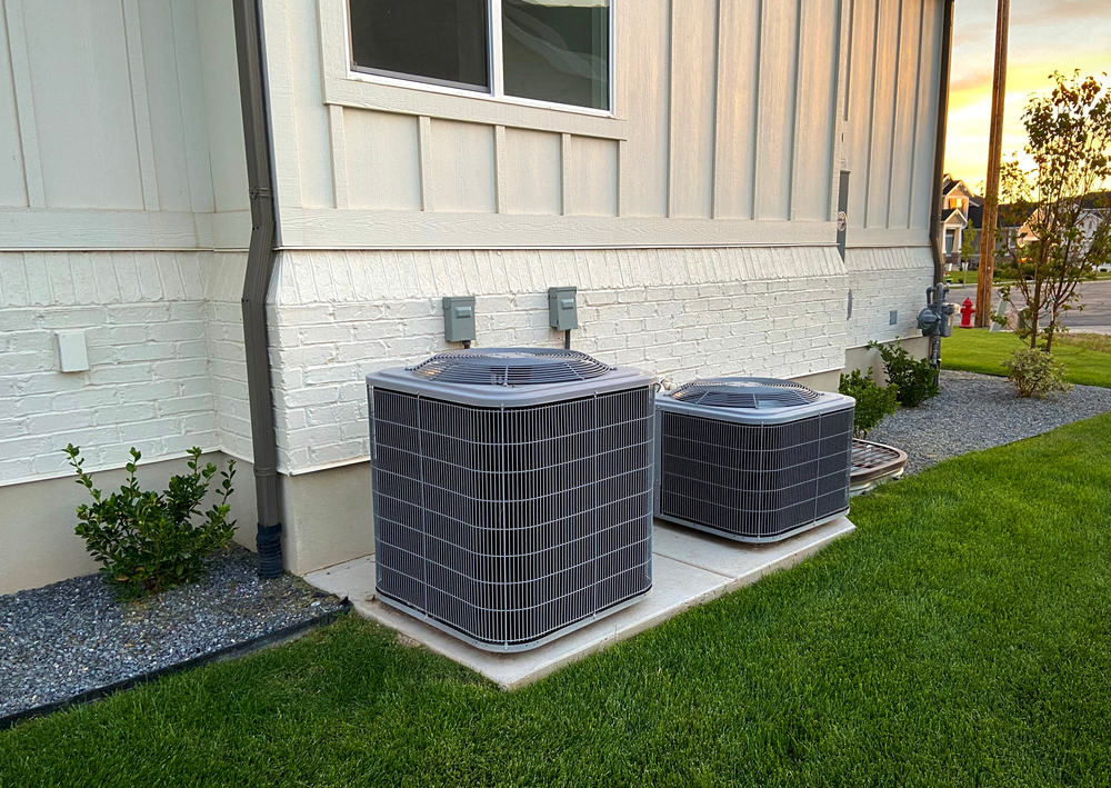Double Ac Units Outside White Brick Home With Green Landscape
