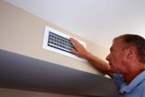 man inspecting HVAC vent