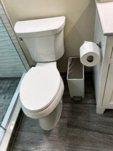 toilet with garbage and toilet paper nearby