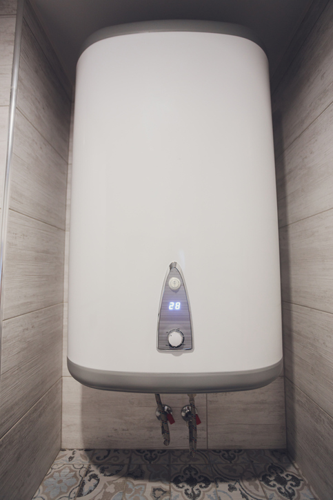 Instant tankless electric water heater installed on white tile wall